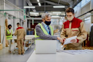 mid adult engineer male worker wearing face masks while examining paperwork woodworking factory 1